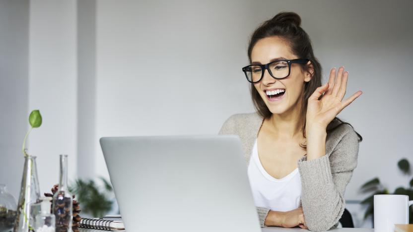 Young woman laughing during video chat at desk