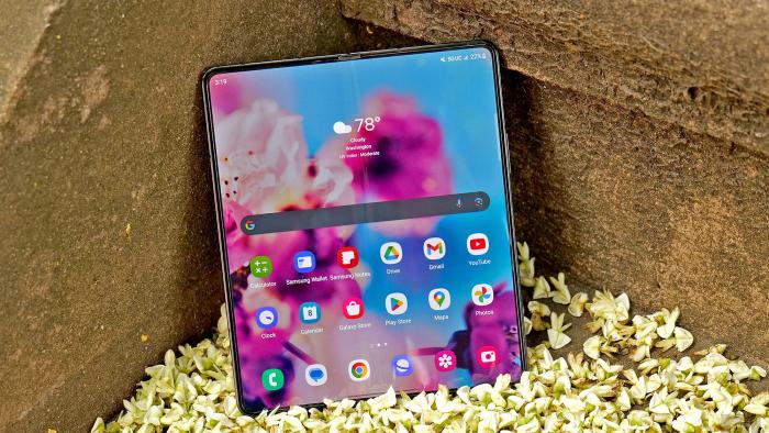 Photo of the Samsung Galaxy Z Fold 5 sitting on an outdoor step on top of wilted flower petals. Its display is open to its home screen.