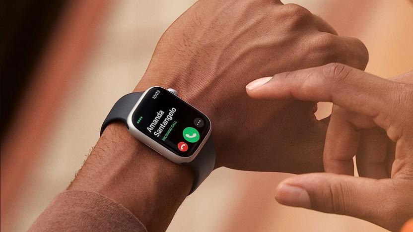 The Apple Watch 8 is seen being worn on a wrist while the other hand aims to poke at an onscreen icon in this cropped photo.