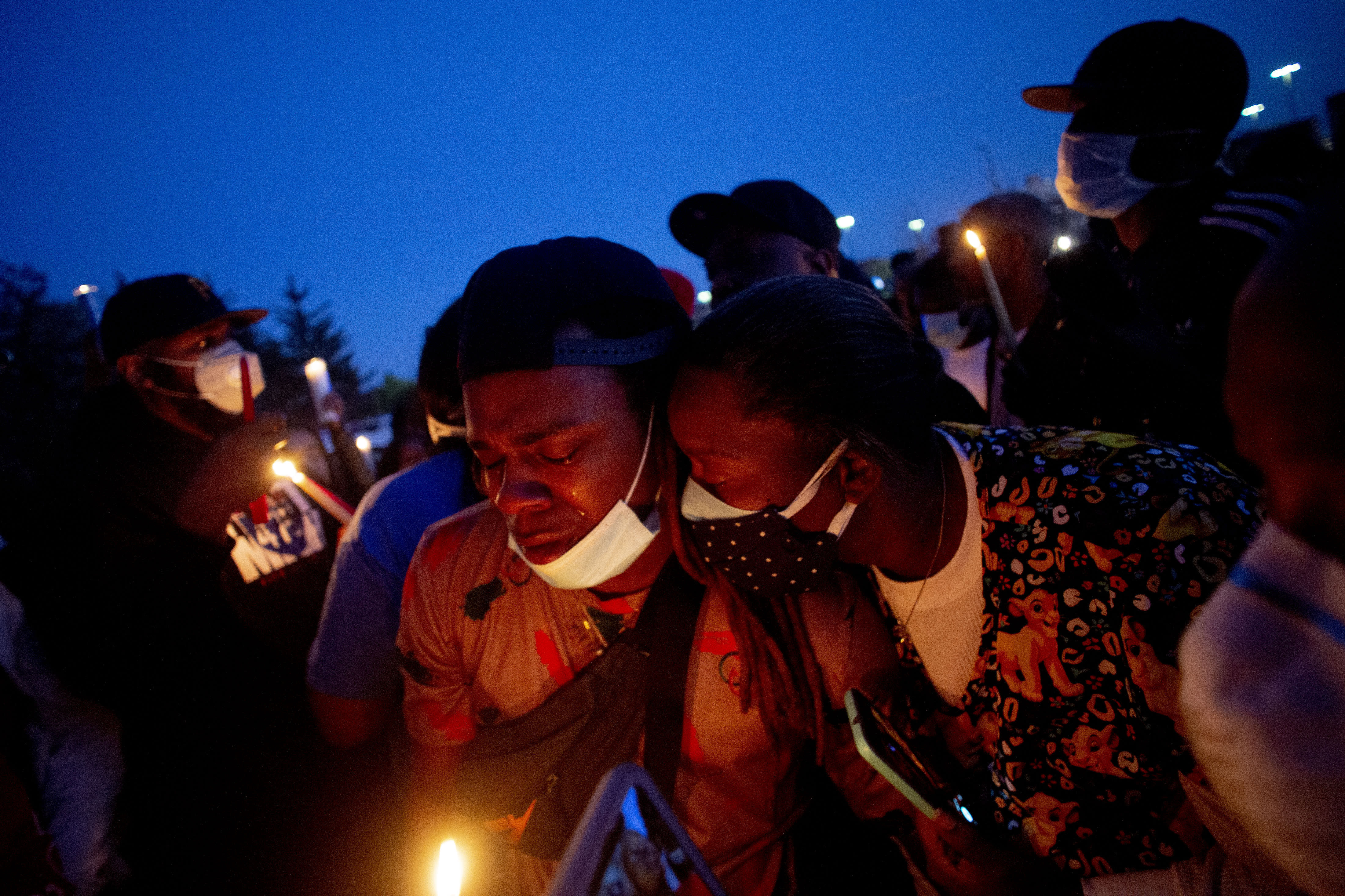 Maalik Mitchell, center left, sheds tears as he says goodbye to his father, Calvin Munerlyn, during a vigil Sunday, May 3, 2020, in Flint, Mich. Munerlyn was shot and killed Friday at a Family Dollar store in Flint. He'd worked at the store as a security guard for a little more than one year. (Jake May/The Flint Journal via AP)