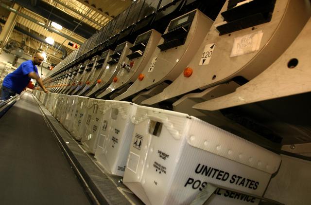 CAPITOL HEIGHTS, UNITED STATES:  A postal employee attends to an automated sorting machine at the United States Postal Service's processing and distribution center in Capitol Heights, Maryland, 19 December 2002.  The processing and distribution center, which operates 24-hours a day, expects to handle some 800,000 pieces of mail 19 December 2002, two times the normal amount, as Christmas approaches. AFP PHOTO / Robyn BECK (Photo credit should read ROBYN BECK/AFP via Getty Images)