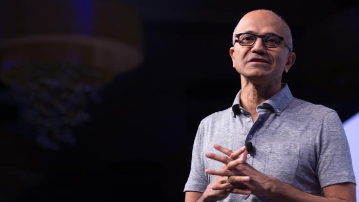 A man wearing a polo shirt and a pair of glasses with his hands clasped in front of him. 