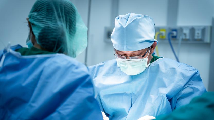 Close up face of Surgeons working surgical stitches are in progress during Operation. Professional Medical Doctors Performing Surgery and Assistant Hands out Instruments inside modern operating room