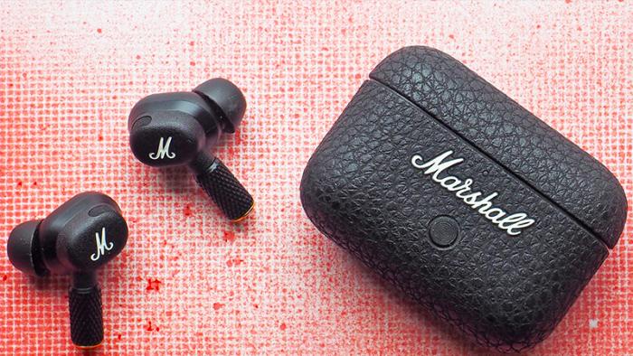 The Marshall Motif II ANC earbuds and charging case with a gridded red spray paint background.