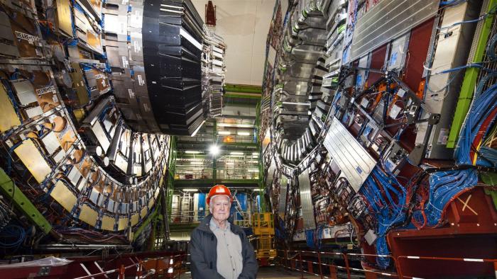 Peter Higgs standing in front of the Large Hadron collider.