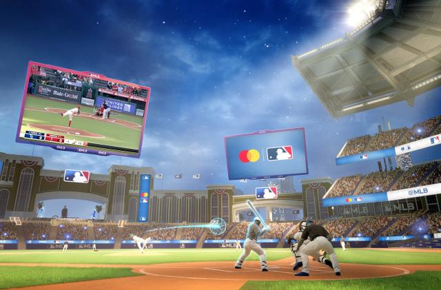 3D digital "space" featuring a baseball stadium showing avatars on the field playing a game. View from behind and slightly to the left of home plate. A real television broadcast of the game is visible on a giant floating Jumbotron in center field.