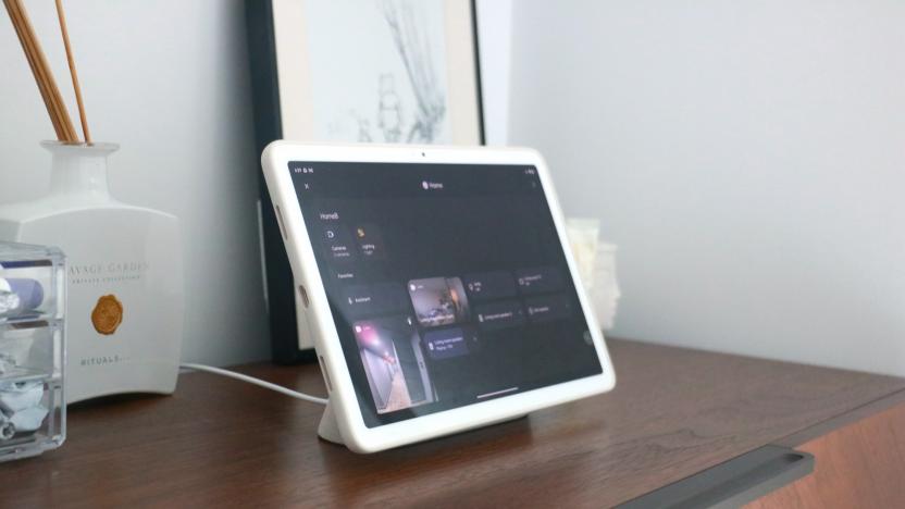 The Pixel Tablet on a walnut dresser showing the smart home dashboard in Hub Mode.