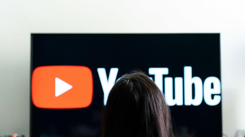 A woman seen sitting in front of a tv screen that  shows the logo of You Tube platform. (Photo by Nikos Pekiaridis/NurPhoto via Getty Images)