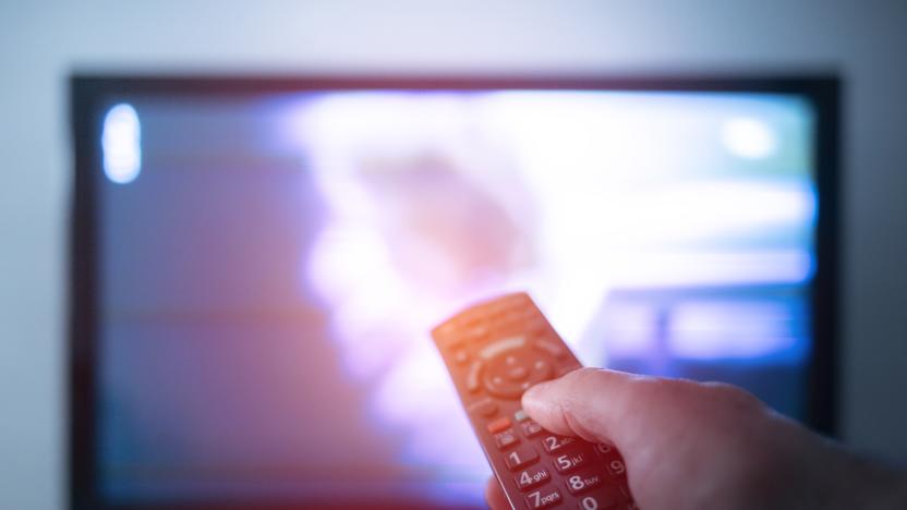 Hand with remote control in front of the tv