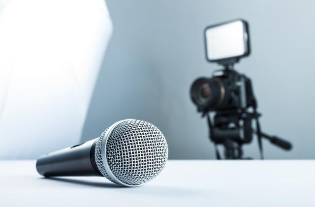 A wireless microphone lying on a white table against the background of the DSLR camera to led light.