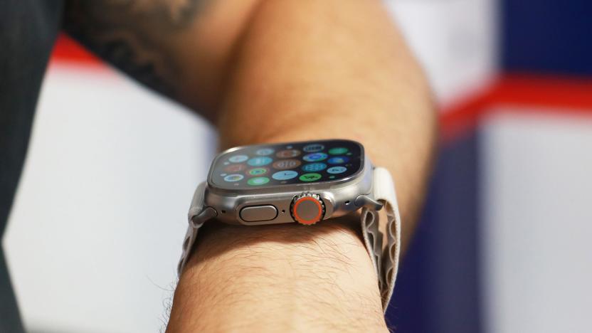 Side view of the Apple Watch Ultra on a person's wrist, showing the apps gallery on its screen. Facing the camera are the watch's Digital Crown with an orange ring on it, as well as the dock button.