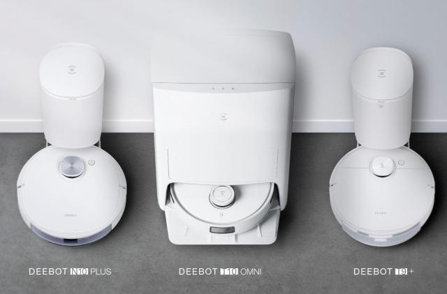 Side-by-side image from above of three docked robot vacuums on a dark gray carpet against a light-colored wall. The three vacuums are labeled (left to right): Deebot N10 Plus, Deebot T10 Omni and Deebot T9+.