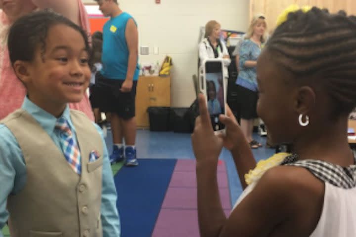 Kindergarteners take photos of each other at graduation and yes, we need a tissue