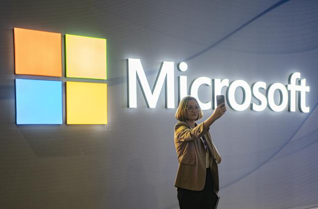 FILE - A visitor takes a photo at the Microsoft stand at Mobile World Congress 2024 in Barcelona, Spain, Feb. 27, 2024. New European Union rules aimed at preventing tech companies from dominating digital markets will change what people see online starting Thursday, March 7, 2024. (AP Photo/Pau Venteo, File)