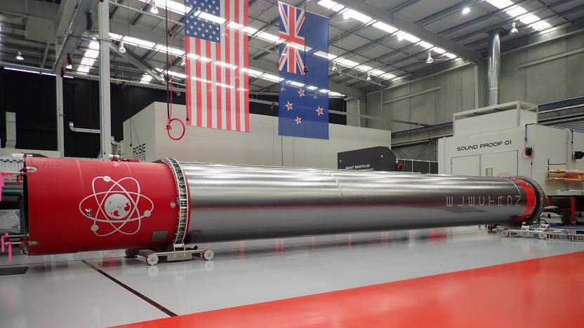 The Rocket Lab booster rocket seen in is storage hangar with a large red strip on the floor and red-capped ends on the rocket itself.