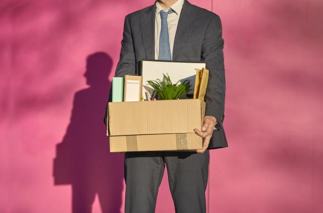 Businessman carrying box with personal belongings on sunny day