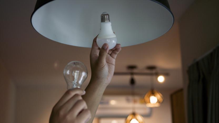 Male hands compare an incandescent light bulb and a LED lamp