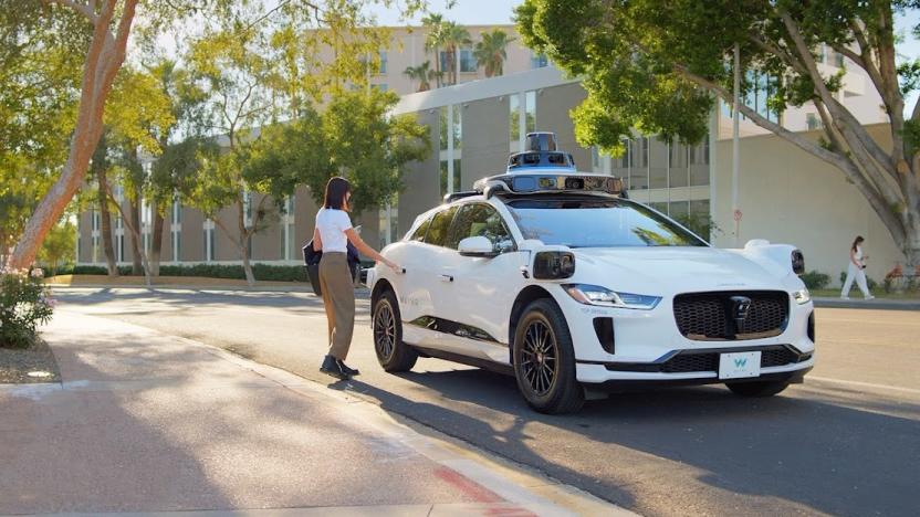 A person reaching out to open the backdoor of a Waymo robotaxi. Serene treelined street.