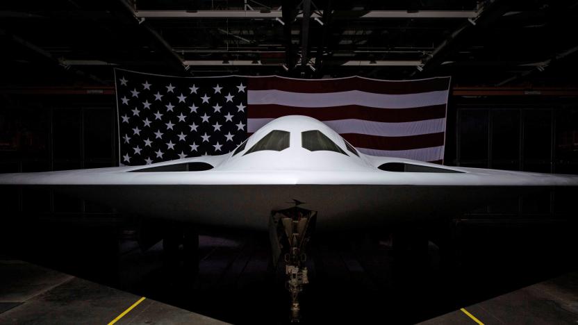 The Northrop Grumman B-21 Raider aircraft photographed in the hangar with an American flag behind it.