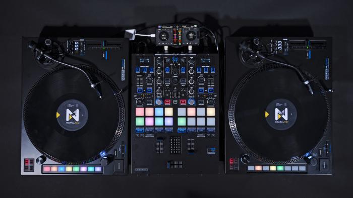 An overhead view of a DJ setup showing two turntables with control discs on them alongside a Reloop DJ mixer and an iPhone which now supports a digital vinyl system (DVS). 