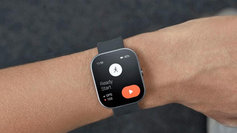 A rectangular-faced smartwatch with rounded edges and a grey band is shown in close-up on a person's wrist. 