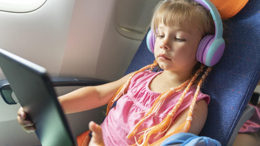 Caucasian girl with headphones watching and listening in flight entertainment on board an airplane