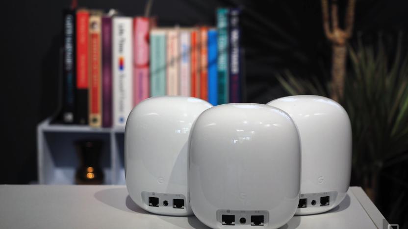 Image of three Nest WiFi Pro units, rear-on, in front of a blurred bookcase.