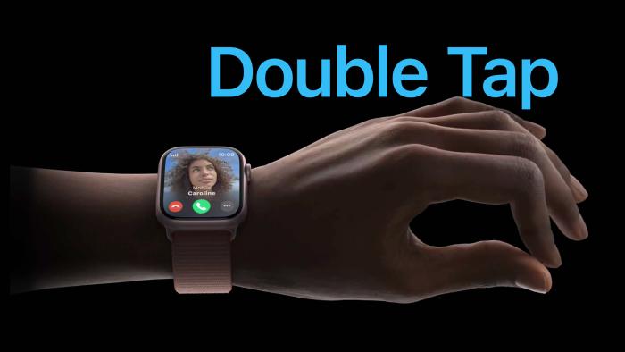 Apple marketing image for the Double Tap feature on Apple Watch. Dark scene (black background) with closeup on a person's wrist and hand. They're wearing an Apple Watch with an incoming call, and the person's hand is making a pinching gesture with the thumb and index finger.