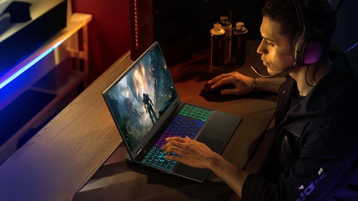 Product lifestyle marketing photo for the Acer Nitro 16 gaming laptop. A young adult gamer sits in a posh room with neon lighting playing a game on the laptop (with RGB glowing keys).