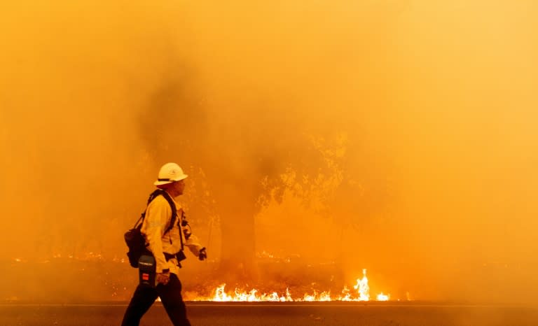 A Pacific Gas and Electric firefighter walks down a road as flames approach in Fairfield, California during the LNU Lightning Complex fire on August 19, 2020