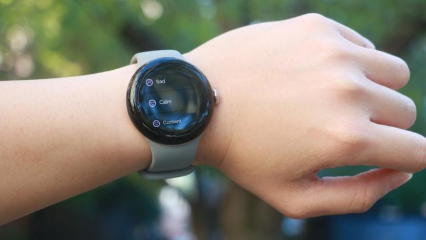 The Google Pixel Watch 2 on a person's left wrist, which is held up horizontally. The screen shows a list of feelings to log, including "Sad," "Calm" and "Content."