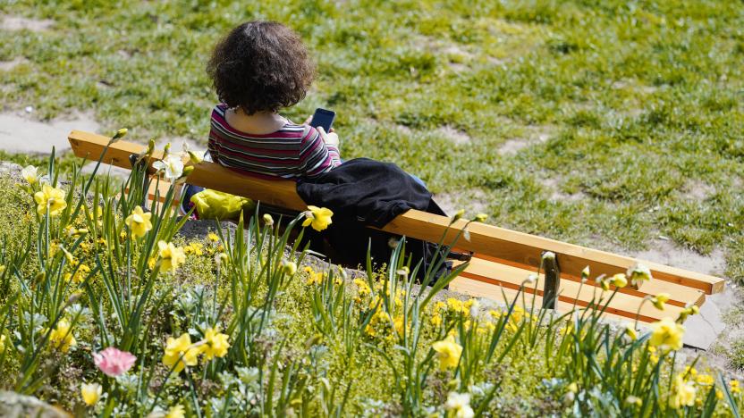 28 March 2020, Baden-Wuerttemberg, Heidelberg: A woman sits alone on a park bench with her cell phone in her hand. Due to the Corona crisis, curfew is currently in effect. Conglomerations of more than two people are prohibited nationwide. Photo: Uwe Anspach/dpa (Photo by Uwe Anspach/picture alliance via Getty Images)