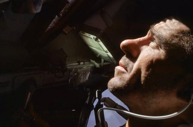 Archival photo of Walter Cunningham looking outward from a capsule into space.