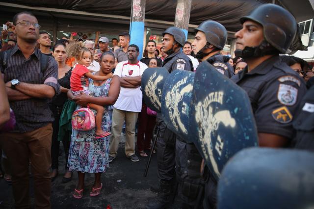 Military police guard the Olympic torch route as onlookers gather. (Getty Images)