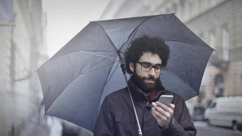 Man is walking on the street with an umbrella and his phone