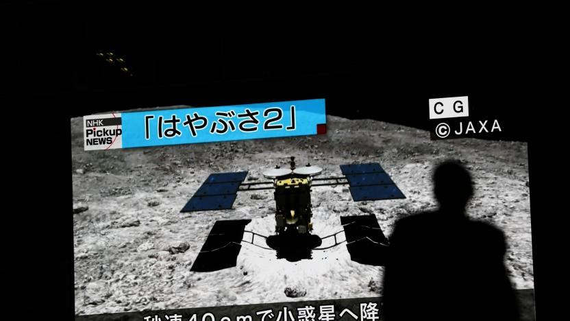 In this picture taken on July 10, 2019 a man walks past a screen displaying a computer-generated image of the Hayabusa2 probe, during a news broadcast at Akihabara district in Tokyo. - Japan's Hayabusa2 probe landed successfully on a distant asteroid for a final touchdown on July 11, 2019, hoping to collect samples that could shed light on the evolution of the solar system. (Photo by Behrouz MEHRI / AFP)        (Photo credit should read BEHROUZ MEHRI/AFP/Getty Images)