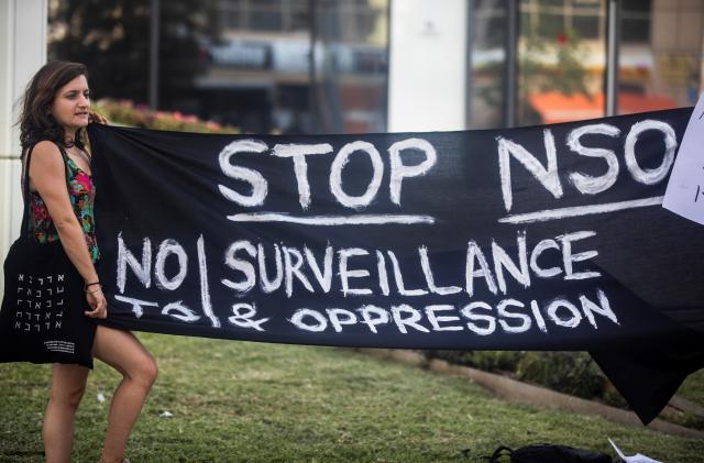 A protester holds a banner during a protest attended by about a dozen people outside the offices of the Israeli cyber firm NSO Group in Herzliya near Tel Aviv, Israel July 25, 2021. REUTERS/Nir Elias