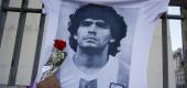 A man places a flower on a jersey with the face of the late soccer star Diego Maradona. (AP)