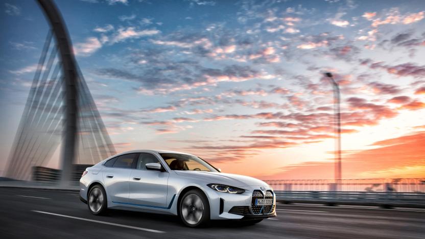 BMW marketing photo of the i4 xDrive 40 EV. The silver car is driving along a bridge in front of a beautiful sky at sunset.