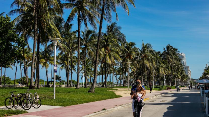 A couple rides an electric scooter on Ocean Drive in South Beach, Miami, on June 9, 2020. - Miami-Dade County beaches that were closed due to coronavirus pandemic will open on June 10, with visitors required to follow new social distancing guidelines. (Photo by CHANDAN KHANNA / AFP) (Photo by CHANDAN KHANNA/AFP via Getty Images)