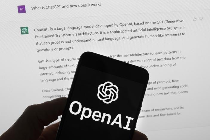 El logotipo de OpenAI puede apreciarse en un teléfono celular frente a la pantalla de una computadora que muestra los resultados de una búsqueda en Chat GPT, el 21 de marzo de 2023, en Boston. (AP Foto/Michael Dwyer, Archivo)