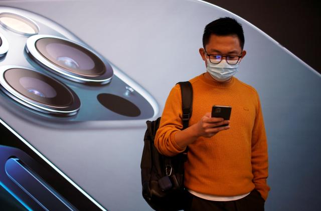 A man wears a face mask while waiting at an Apple Store before Apple's 5G new iPhone 12 go on sale, as the coronavirus disease (COVID-19) outbreak continues in Shanghai China October 23, 2020. REUTERS/Aly Song