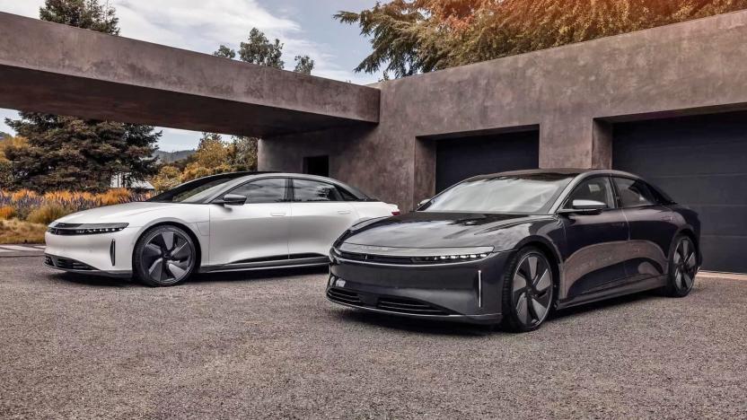 Two Lucid Air EVs in black and white with the Stealth Look trim are parked on a gravel driveway.