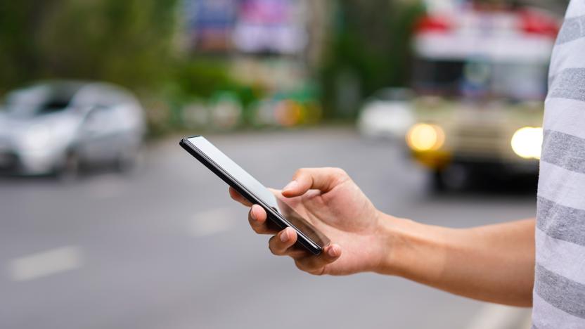 Hand of man using a mobile phone on the street. Use of transportation app