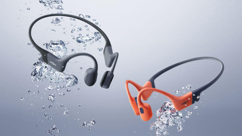 Two Shokz OpenSwim Pro headsets are shown surrounded by watery bubbles as if they were submerged in water.