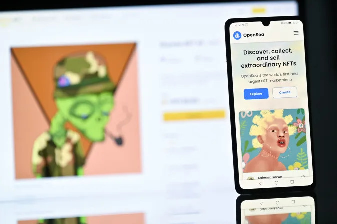 An illustration picture taken in London on December 30, 2021, shows a NFT (Non-Fungible Token) created by Nigerian digital artist FreddieJacobArt named "Oghenerukevwe" on Opensea NFT marketplace, displayed on a phone and Binance NFT marketplace displayed on a computer screen. - Non-fungible tokens or NFTs are cryptographic assets stored on a blockchain with unique identification metadata that distinguish them from each other.- RESTRICTED TO EDITORIAL USE - MANDATORY MENTION OF THE ARTIST UPON PUBLICATION - TO ILLUSTRATE THE EVENT AS SPECIFIED IN THE CAPTION (Photo by Justin TALLIS / AFP) / RESTRICTED TO EDITORIAL USE - MANDATORY MENTION OF THE ARTIST UPON PUBLICATION - TO ILLUSTRATE THE EVENT AS SPECIFIED IN THE CAPTION / RESTRICTED TO EDITORIAL USE - MANDATORY MENTION OF THE ARTIST UPON PUBLICATION - TO ILLUSTRATE THE EVENT AS SPECIFIED IN THE CAPTION (Photo by JUSTIN TALLIS/AFP via Getty Images)