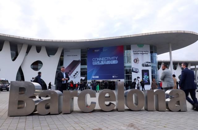 People walk past a "Barcelona" sign outside GSMA's 2022 Mobile World Congress (MWC) in Barcelona, Spain February 28, 2022. REUTERS/Nacho Doce