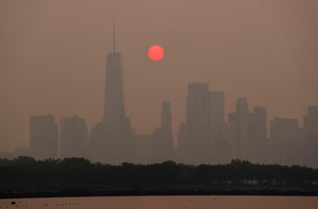 JERSEY CITY, NJ - JUNE 7: Smoke continues to shroud the sun as it rises behind the skyline of lower Manhattan and One World Trade Center in New York City on June 7, 2023, as seen from Jersey City, New Jersey.  (Photo by Gary Hershorn/Getty Images)