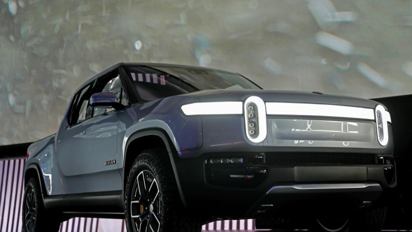 A Rivian EV pickup truck on display at an auto show, on stage by itself.