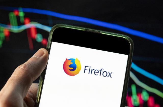 In this photo illustration the open-source web browser developed by Mozilla Foundation, Firefox logo seen displayed on a smartphone with an economic stock exchange index graph in the background. 